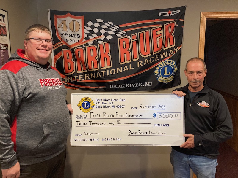 Accepting the check for the Ford River Fire Department is Fire Chief Brian Nelson with the check being presented by Bark River Lions Club President Brian Farrell.